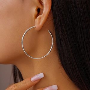 Close-up of polished silver C-shaped hoop earrings on model for a minimalist style