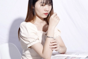 Minimalist silver C-shaped open bangle shown on model wrist against white background