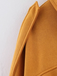 Close-up of mustard yellow suede texture and precise stitching on the bomber jacket
