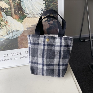 Detailed view of the checkered plaid wool lunch bag with metal buckle and woven handle