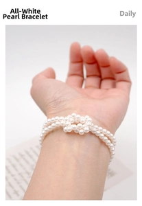 Detail of double-layer white pearl bracelet featuring an elegant knotted wrap design