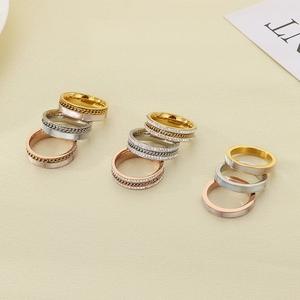 Close-up of stacked fashion rings with zircon inlay and chain texture in gold, silver, rose gold