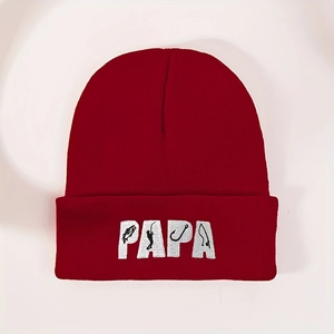 Dettaglio del ricamo PAPA con motivi da pesca su un berretto in maglia rossa