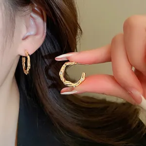 Gold C-shaped irregular earrings with hammered texture and cubic zirconia accents