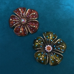Macro detail of vintage enamel flower brooches with sparkling rhinestone petals and leaf
