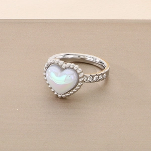 Close-up of silver ring featuring iridescent heart shell inlay and sparkling zirconia stones