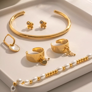 Close-up of gold jewelry set with star pendant ring and pearl necklace on a ceramic tray