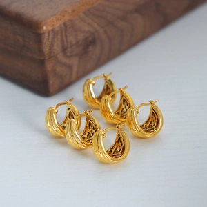 Three pairs of vintage 18K gold plated U-shaped textured hoop earrings on a wood background