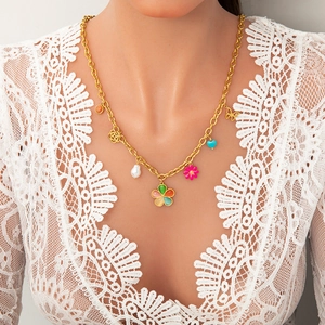 Close-up of golden necklace with colorful flower, butterfly, and pearl charms on a model