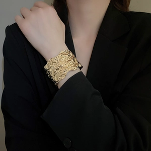 Macro shot of gold wide open cuff bracelet featuring artistic irregular wrinkled textures