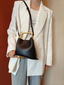 Close-up of black leather bucket bag with gold metal top handle and structured design
