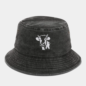 Detailed view of white cow embroidery and metal eyelets on dark grey washed denim bucket hat
