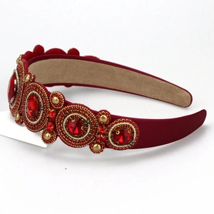 Close-up of red velvet baroque headband with ornate gold beads and large faceted gems