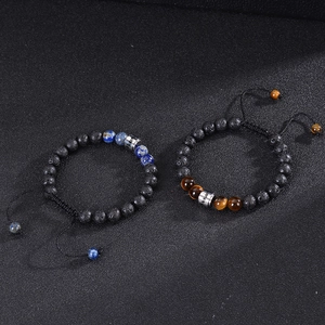 Close-up of black lava stone bracelets with custom engraved metal beads and tiger eye stones