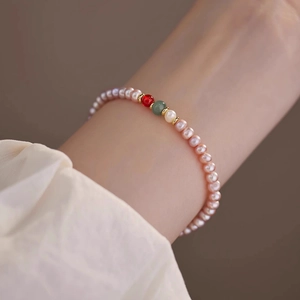 Detail of freshwater pearl bracelet with agate stones on wrist in soft lighting