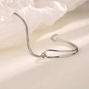 Macro view of minimalist silver chain bracelet with polished geometric arc element