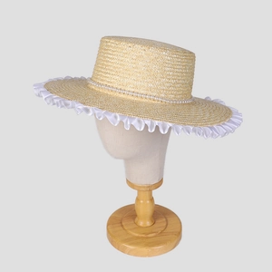 Detail of wheat straw boater hat with white lace trim and elegant pearl band decoration