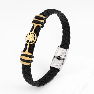 Close-up of black braided leather bracelet with golden maple leaf metal ornament and silver clasp