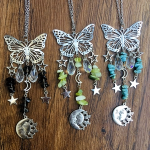 Three silver butterfly suncatchers with crystal balls and moon pendants on wood