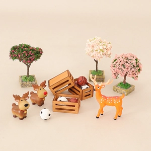 Miniature dollhouse set with plastic deer figures, tiny flowering trees, and sports balls