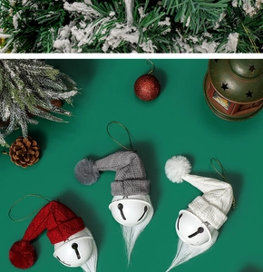 Close-up of three Christmas gnome bells in red, grey and white on green pine branches