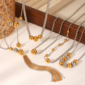 Two-tone 18K gold and silver bead Y-necklace with long tassel on a wooden tray