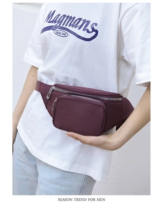 Detailed view of burgundy waterproof waist bag worn by a model in casual style
