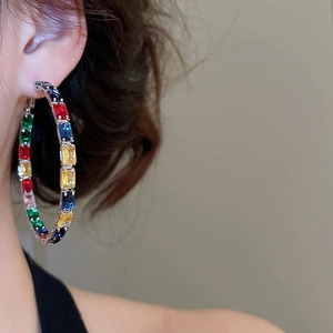 Detail view of large silver hoop earrings featuring multi-color rectangular zircon stones