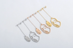 Vue détaillée de boucles d'oreilles visage abstrait en argent, or et or rose poli