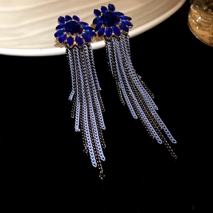 Détail macro de boucles d'oreilles vintage avec pierres bleues et longues franges chic