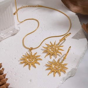 Golden sun spiral pendant necklace and matching earrings set on white stone