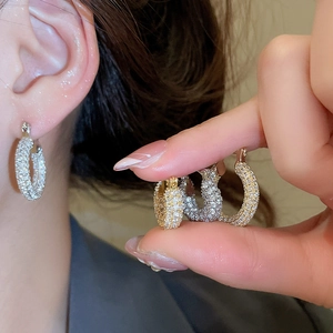 Close-up of gold and silver U-shaped earrings with micro-paved sparkling zircon stones
