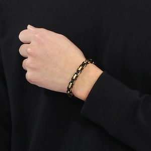 Bracelet chaîne à maillons carrés pour homme en acier noir et or porté au poignet style hip hop