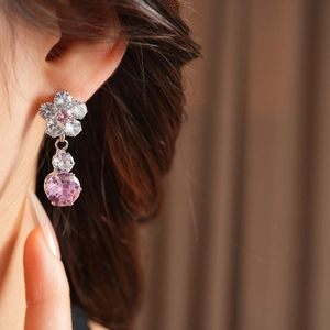 Close-up of elegant flower earrings with pink and clear zircon stones on a model