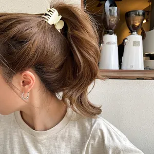 Elegante pinza per capelli beige opaco e orecchini a cerchio argento su modella