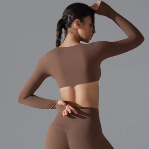 Dettaglio del top da yoga marrone a maniche lunghe con fori per i pollici e vestibilità slim