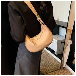 Dettaglio della borsa a mezzaluna beige in pelle martellata e fibbia dorata sul cinturino