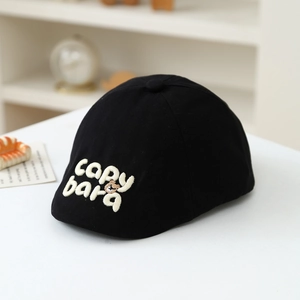 Detailed close-up of embroidered Capybara and white letters on a black cotton beret cap