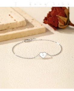 Gros plan d'un bracelet pendentif coeur en argent sur pierre avec une rose rouge séchée