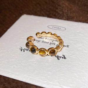 Détail d'une bague dorée ondulée ornée de cinq pierres œil de tigre rondes