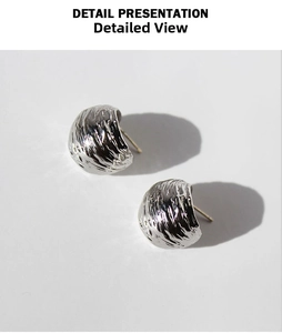 Macro detail of silver-plated C-shape earrings with irregular pleated metal texture