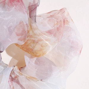 Detailed close-up of floral organza fabric texture with delicate folds and pastel colors