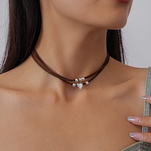 Detail view of double-layered brown leather choker with silver heart and bead pendant