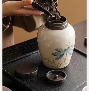 Macro shot of a ceramic tea canister with blue lotus motifs being filled with tea leaves
