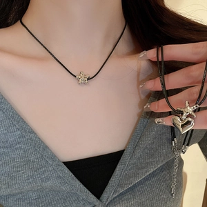 Minimalist silver star and heart pendant necklace with black cord cord on model