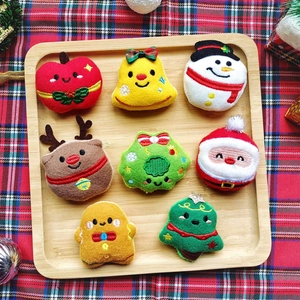 Close-up of 8 Christmas plush charms including snowman and reindeer on a wooden tray