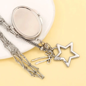 Detail of silver lipstick chain bag with star-shaped clasp and oval locket pendant