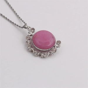 Detail eines rosa Edelstein-Anhängers mit silbernem Mond und Stern an einer Kordelkette