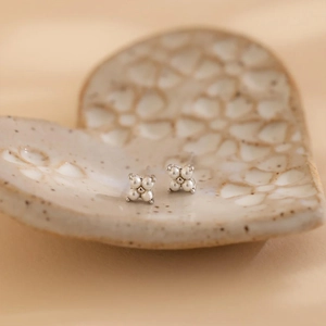 Detailed close-up of four-pearl cluster stud earrings on a heart ceramic tray