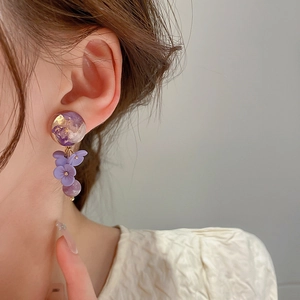 Close-up of long purple floral drop earrings featuring gold leaf resin and flower petals